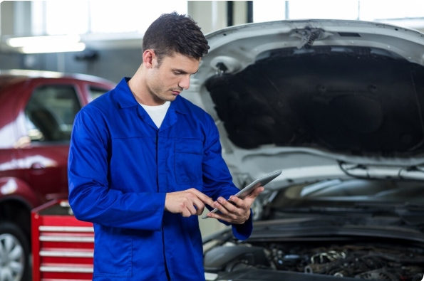 Professional mobile auto technician performing an on-site brake pad replacement in a Dubai parking lot.